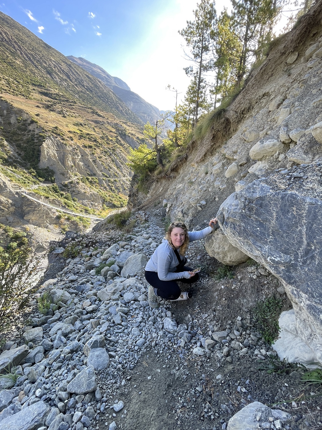 Kayley from Snow Leopard Conservancy in Manang Valley, Nepal, examining signs of a snow leopard's presence.